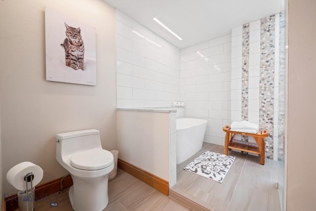 full bathroom featuring a freestanding bath, baseboards, and toilet