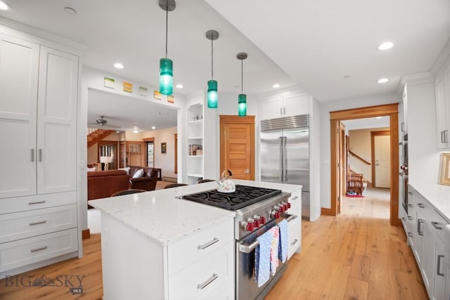 kitchen with light wood finished floors, premium appliances, recessed lighting, and white cabinetry