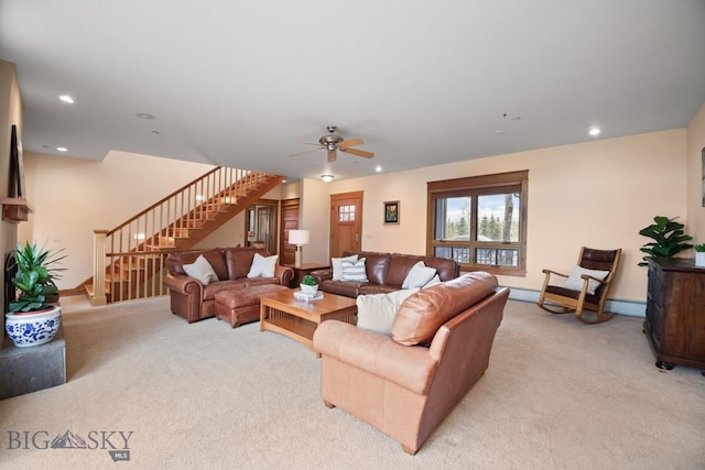 living area with stairway, baseboards, a ceiling fan, and light colored carpet