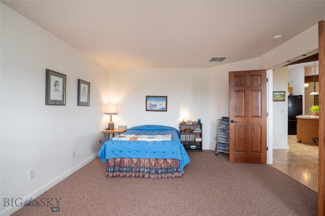 carpeted bedroom with visible vents, freestanding refrigerator, and baseboards