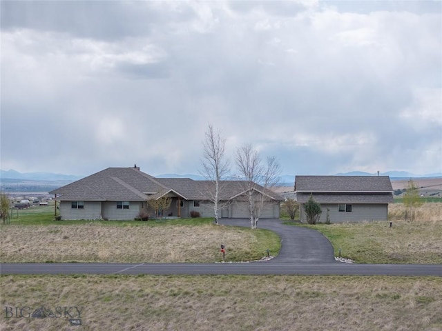 single story home featuring a garage, roof with shingles, and driveway