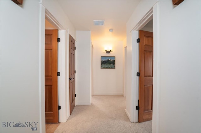 hallway with baseboards, light carpet, and visible vents