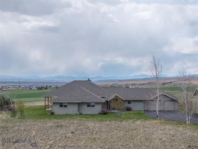 view of front of house featuring an attached garage, a mountain view, driveway, and a front yard