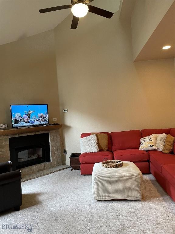 93 8th St Unit B, Belgrade, MT 59714 - carpeted living area featuring a fireplace with raised hearth, ceiling fan, and lofted ceiling
