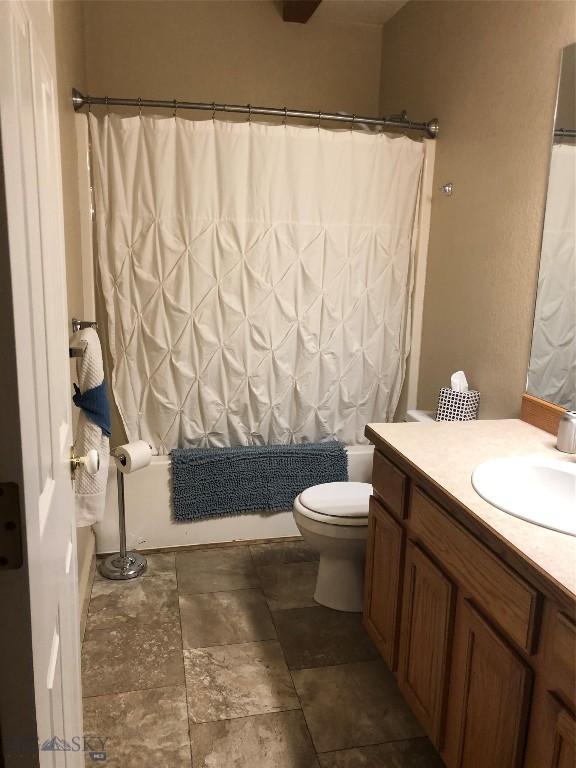 93 8th St Unit B, Belgrade, MT 59714 - full bath featuring vanity, stone finish flooring, toilet, and shower / tub combo