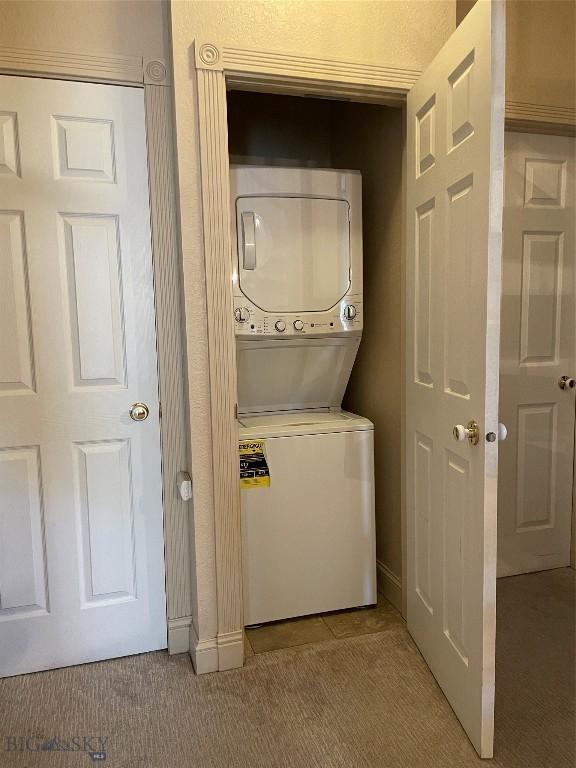 93 8th St Unit B, Belgrade, MT 59714 - laundry room featuring baseboards, light carpet, stacked washer / dryer, and laundry area