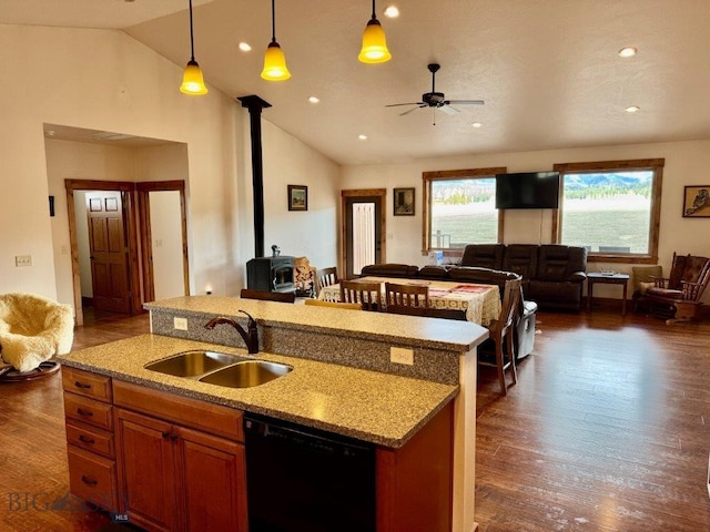 kitchen featuring a wood stove, open floor plan, ceiling fan, black dishwasher, and a sink
