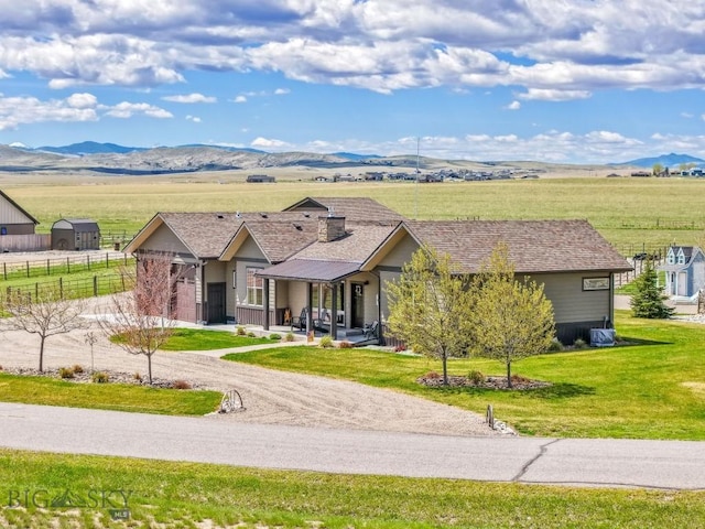 ranch-style home with fence, a mountain view, and a front lawn