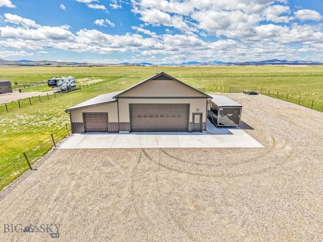 view of front facade with a rural view, fence, an outbuilding, and a garage