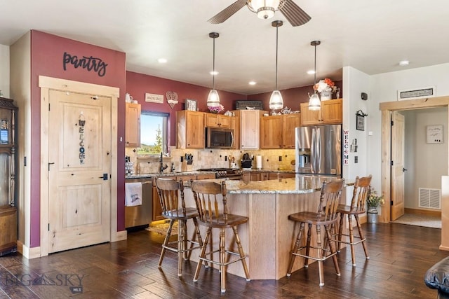 kitchen featuring visible vents, a kitchen bar, light stone counters, appliances with stainless steel finishes, and backsplash