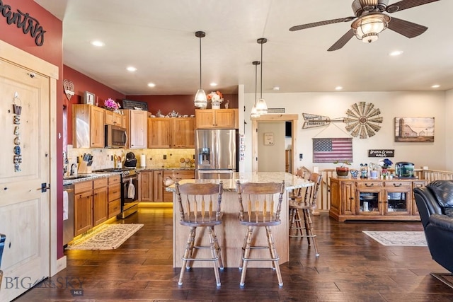 kitchen featuring light stone countertops, a breakfast bar area, recessed lighting, a ceiling fan, and appliances with stainless steel finishes