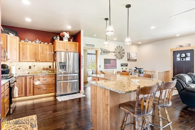 kitchen featuring dark wood-style flooring, a breakfast bar, light brown cabinets, stainless steel appliances, and recessed lighting
