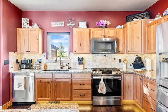kitchen featuring light stone countertops, appliances with stainless steel finishes, a sink, backsplash, and visible vents