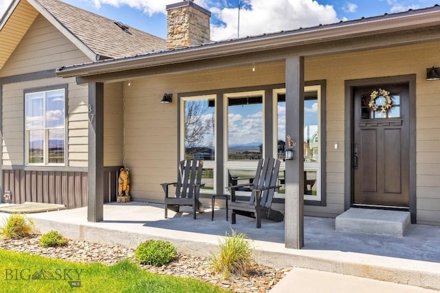 property entrance featuring a porch, a chimney, and a shingled roof