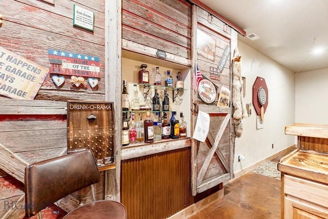 bar featuring baseboards, a dry bar, and concrete floors