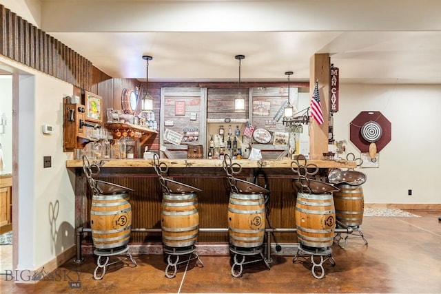 bar with baseboards, pendant lighting, bar area, and finished concrete flooring