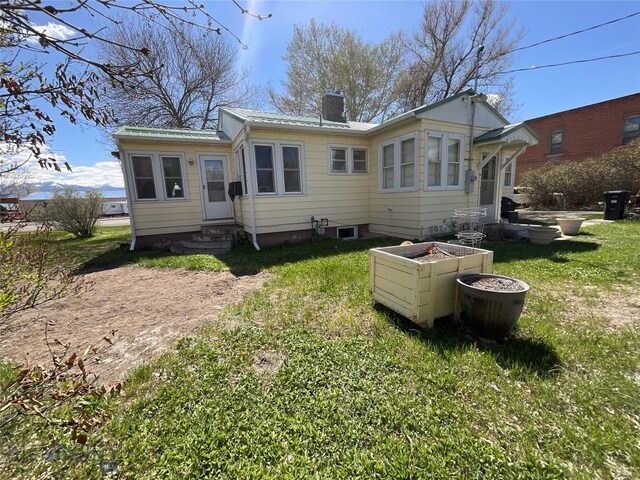 5 1st St W, Whitehall, MT 59759 - rear view of house featuring entry steps, a chimney, a lawn, and a metal roof