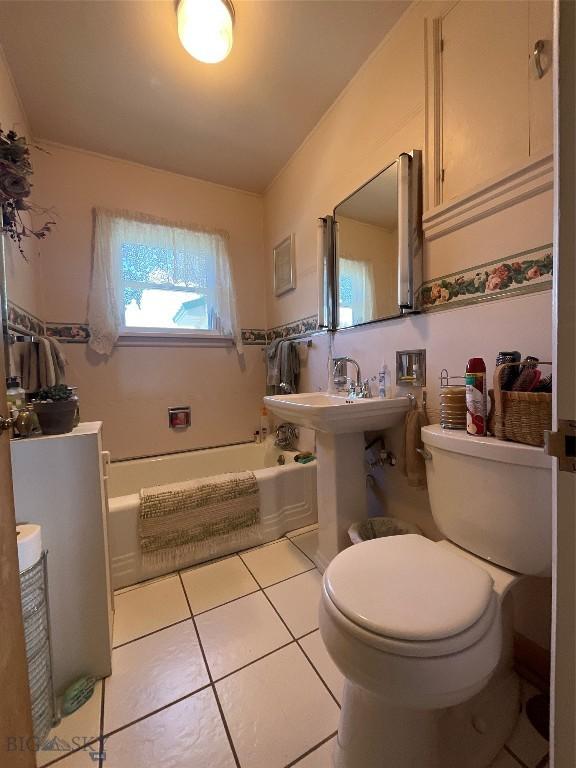 bathroom featuring a bathing tub, toilet, and tile patterned flooring
