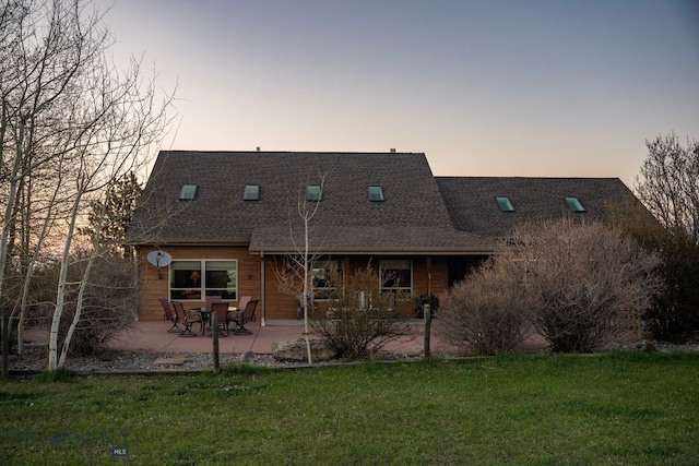 8265 Fowler Ln, Bozeman, MT 59718 - back of property at dusk with a lawn, a shingled roof, and a patio area