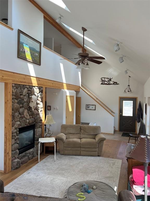 8265 Fowler Ln, Bozeman, MT 59718 - living room with a stone fireplace, wood finished floors, a ceiling fan, and high vaulted ceiling