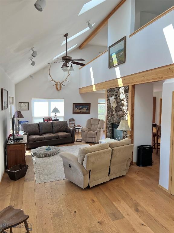 8265 Fowler Ln, Bozeman, MT 59718 - living room featuring high vaulted ceiling, a skylight, light wood-type flooring, a ceiling fan, and beam ceiling