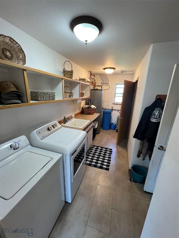 8265 Fowler Ln, Bozeman, MT 59718 - laundry room featuring washing machine and dryer, cabinet space, light tile patterned floors, and water heater