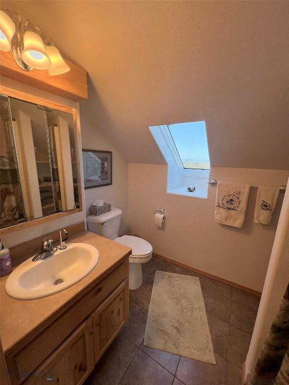 8265 Fowler Ln, Bozeman, MT 59718 - full bath featuring a skylight, lofted ceiling, vanity, toilet, and tile patterned floors