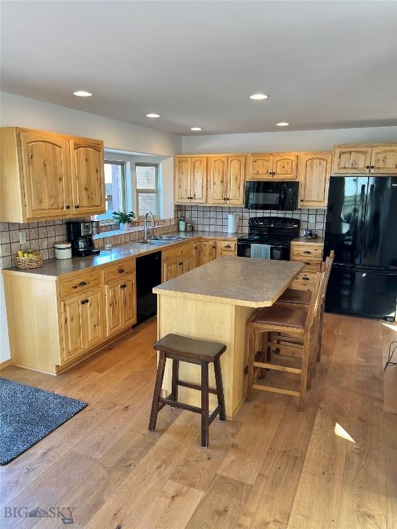 8265 Fowler Ln, Bozeman, MT 59718 - kitchen featuring black appliances, a sink, light brown cabinets, light wood-style flooring, and tasteful backsplash