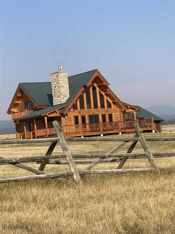 log home featuring a chimney, fence, log exterior, and metal roof