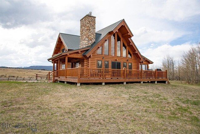 back of house featuring a chimney, a yard, metal roof, log exterior, and a deck