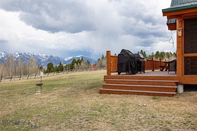 view of yard featuring a deck with mountain view and fence