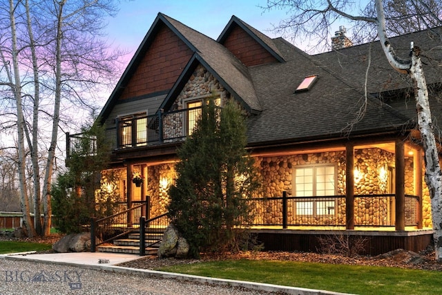 624 Rocking Horse Dr, Bozeman, MT 59718 - view of front of property with roof with shingles, stone siding, a chimney, a balcony, and covered porch