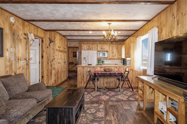 living area with wooden walls, a notable chandelier, dark wood finished floors, and beamed ceiling