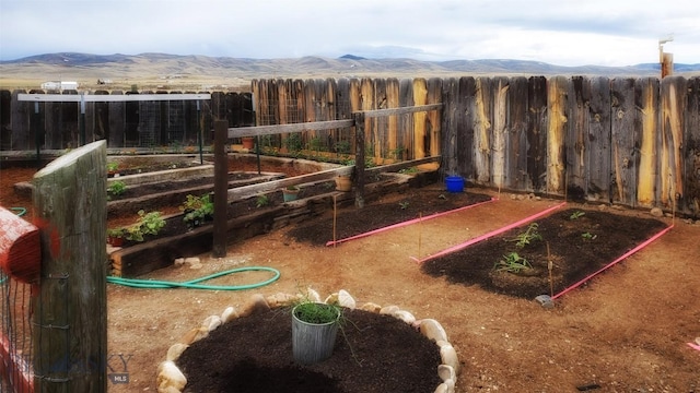 view of playground featuring fence, a mountain view, and a garden