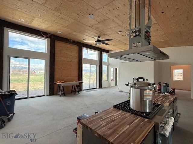kitchen featuring ceiling fan, a towering ceiling, wooden counters, and range