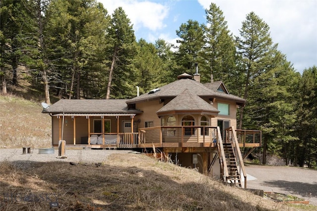 189 Quinn Creek Rd, Bozeman, MT 59715 - view of front of house with stairway, a wooded view, a shingled roof, and a chimney