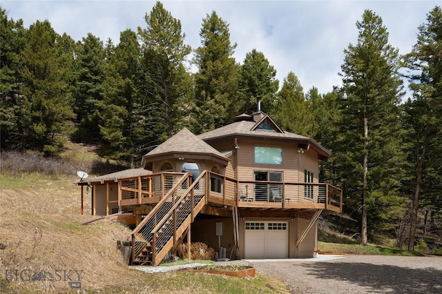 189 Quinn Creek Rd, Bozeman, MT 59715 - view of front of home with an attached garage, a wooded view, a deck, driveway, and stairs