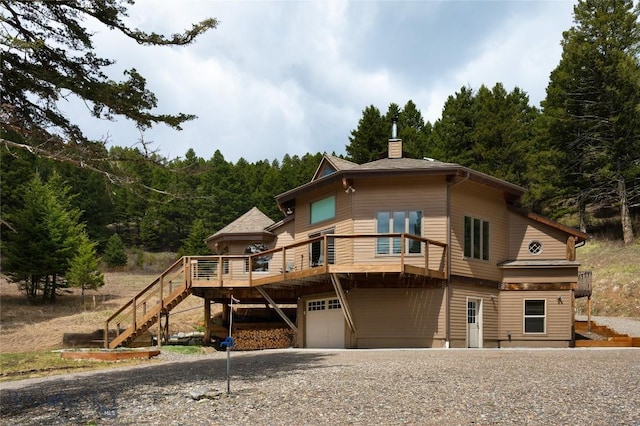 189 Quinn Creek Rd, Bozeman, MT 59715 - view of front of house with stairs, an attached garage, a view of trees, a chimney, and gravel driveway