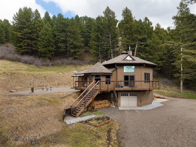 189 Quinn Creek Rd, Bozeman, MT 59715 - view of front of house featuring driveway, a garage, stairway, a wooden deck, and a forest view