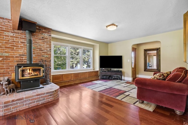 381 Bozeman Trail Rd, Bozeman, MT 59715 - living area with hardwood / wood-style floors, a wood stove, a textured ceiling, arched walkways, and baseboards