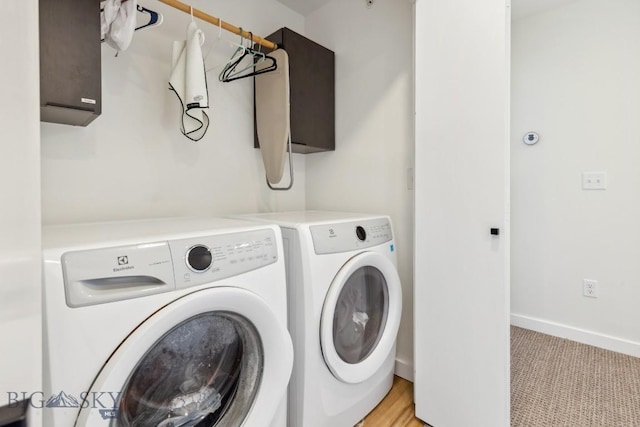 clothes washing area with washing machine and clothes dryer, laundry area, light carpet, and baseboards