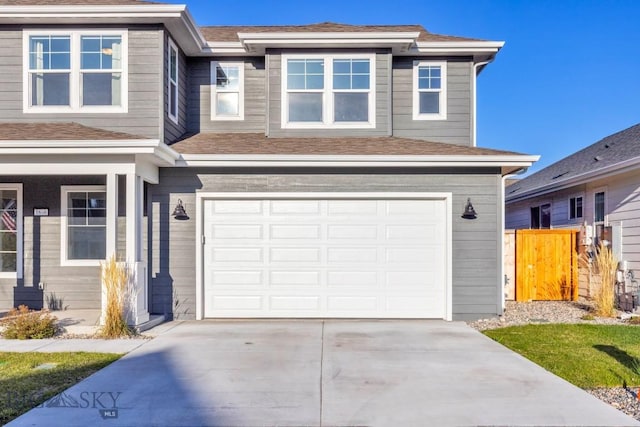 view of front of property featuring concrete driveway, a garage, and fence