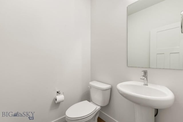 bathroom featuring baseboards, toilet, and a sink