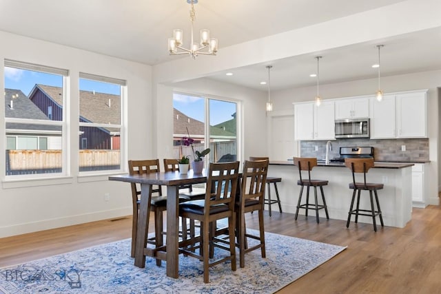 dining room with a notable chandelier, light wood-type flooring, visible vents, baseboards, and recessed lighting