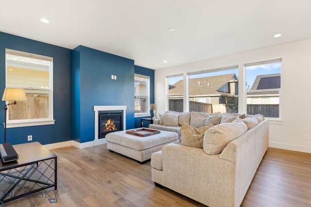living area with recessed lighting, wood finished floors, baseboards, and a glass covered fireplace