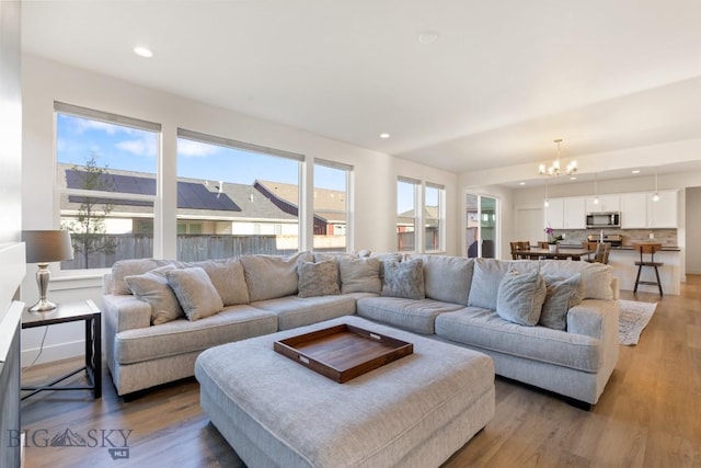 living room featuring light wood-style floors, an inviting chandelier, and recessed lighting