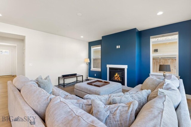 living room with wood finished floors, a glass covered fireplace, and recessed lighting
