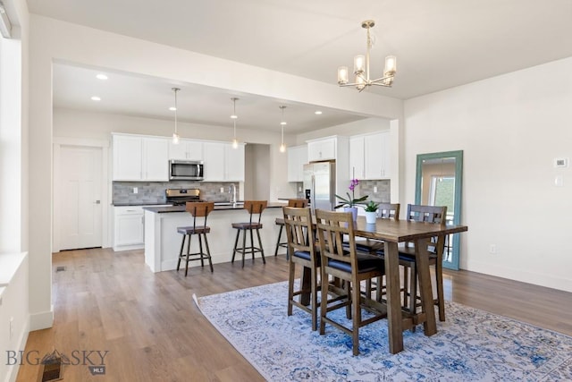 dining area featuring baseboards, an inviting chandelier, recessed lighting, and wood finished floors