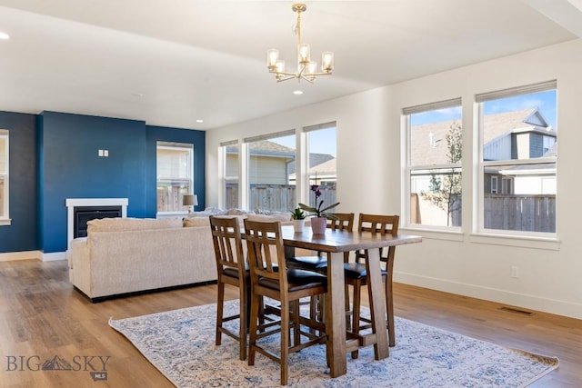 dining room featuring a chandelier, visible vents, wood finished floors, and baseboards