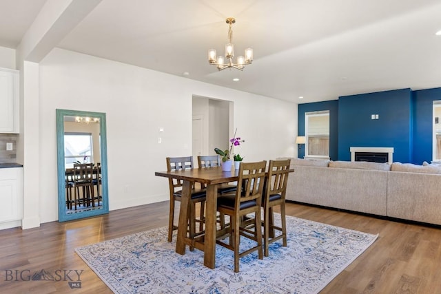 dining area with wood finished floors, a fireplace, baseboards, a chandelier, and recessed lighting